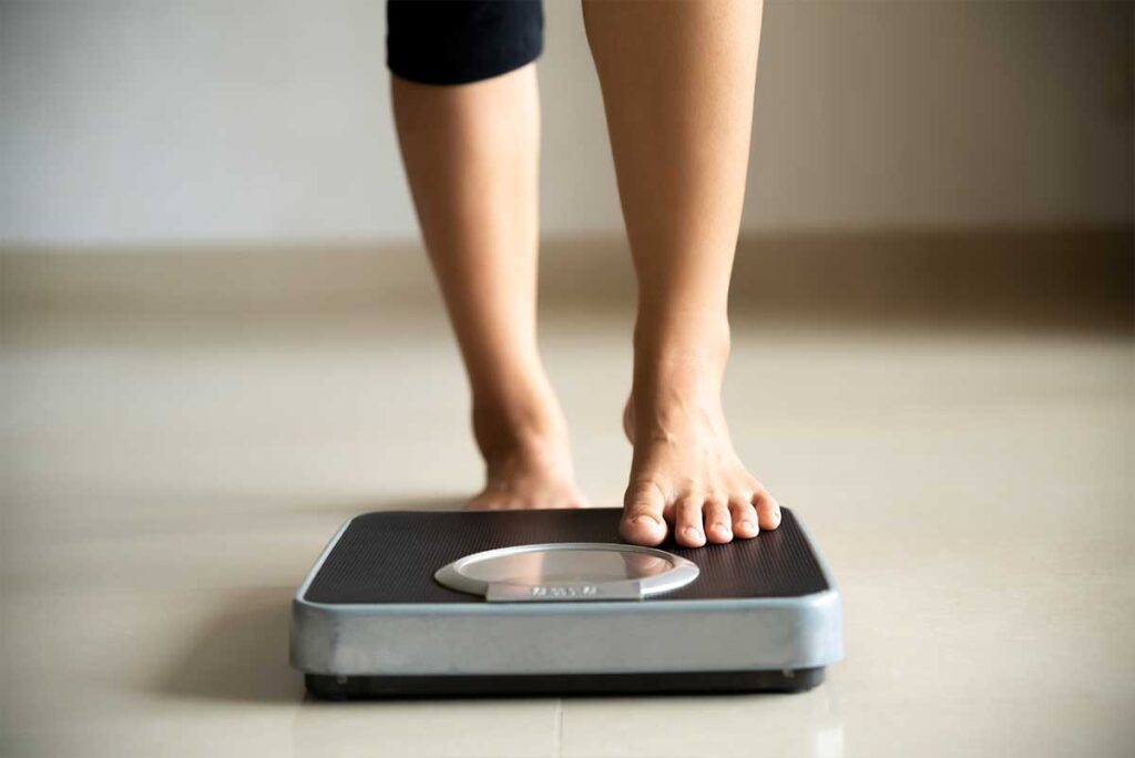 Person stepping onto a weight machine to check weight